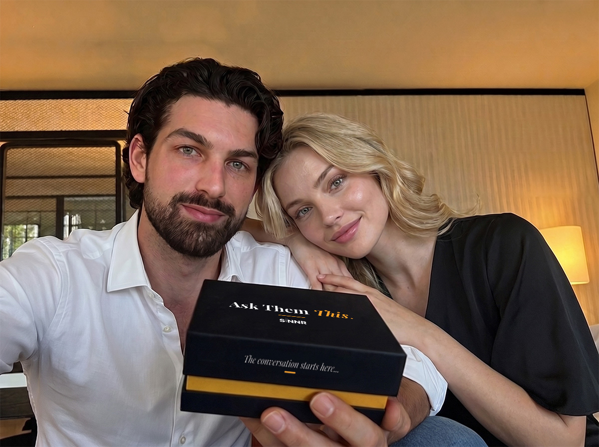 A couple holding the Ask Them This card game box